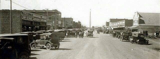 Historic black-and-white photo of early automobiles parked along Main Street in Lockney